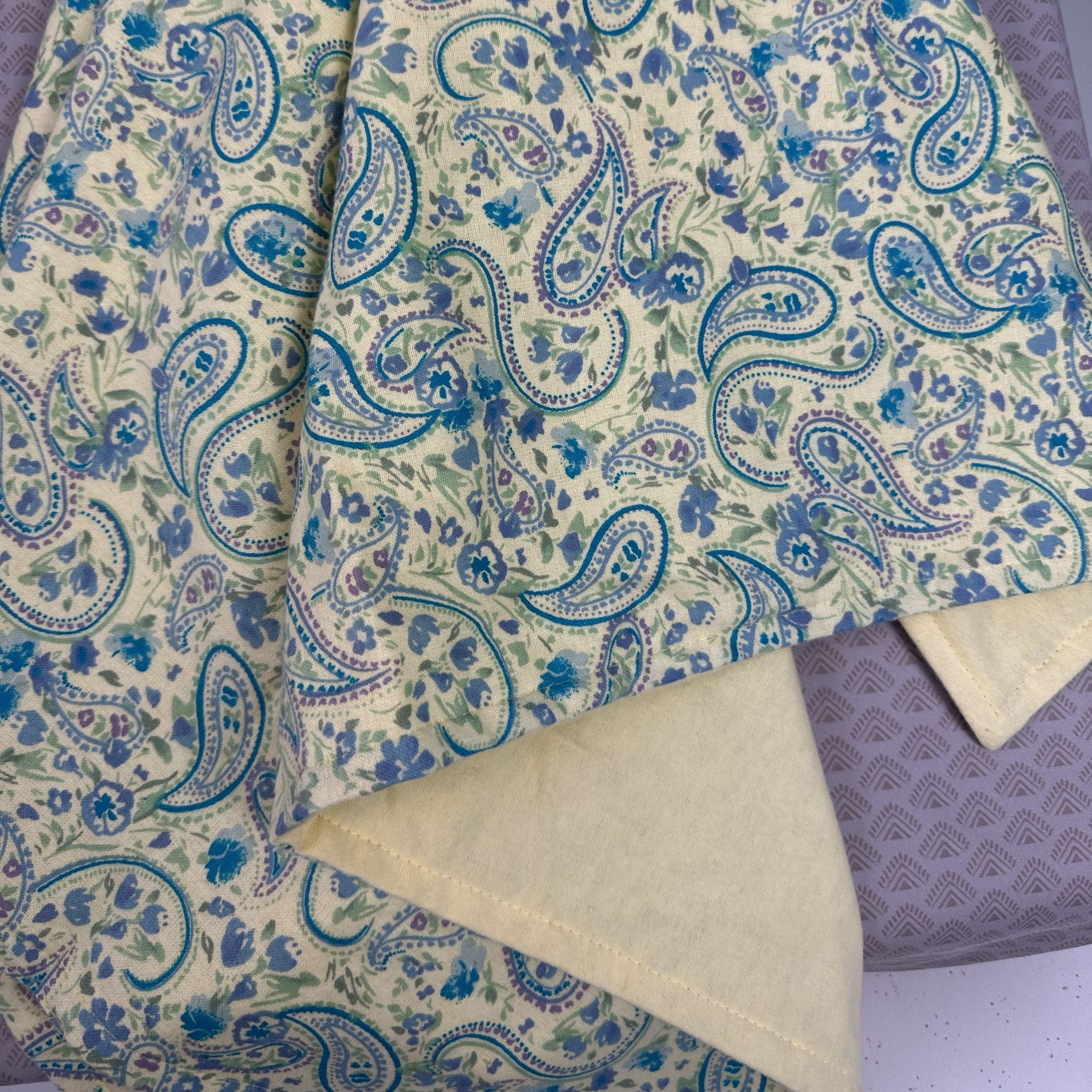 Blue Toby cotton flannel blanket with blue paisley pattern on a butter yellow background