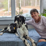 Woman sitting with Great Dane on dog bed